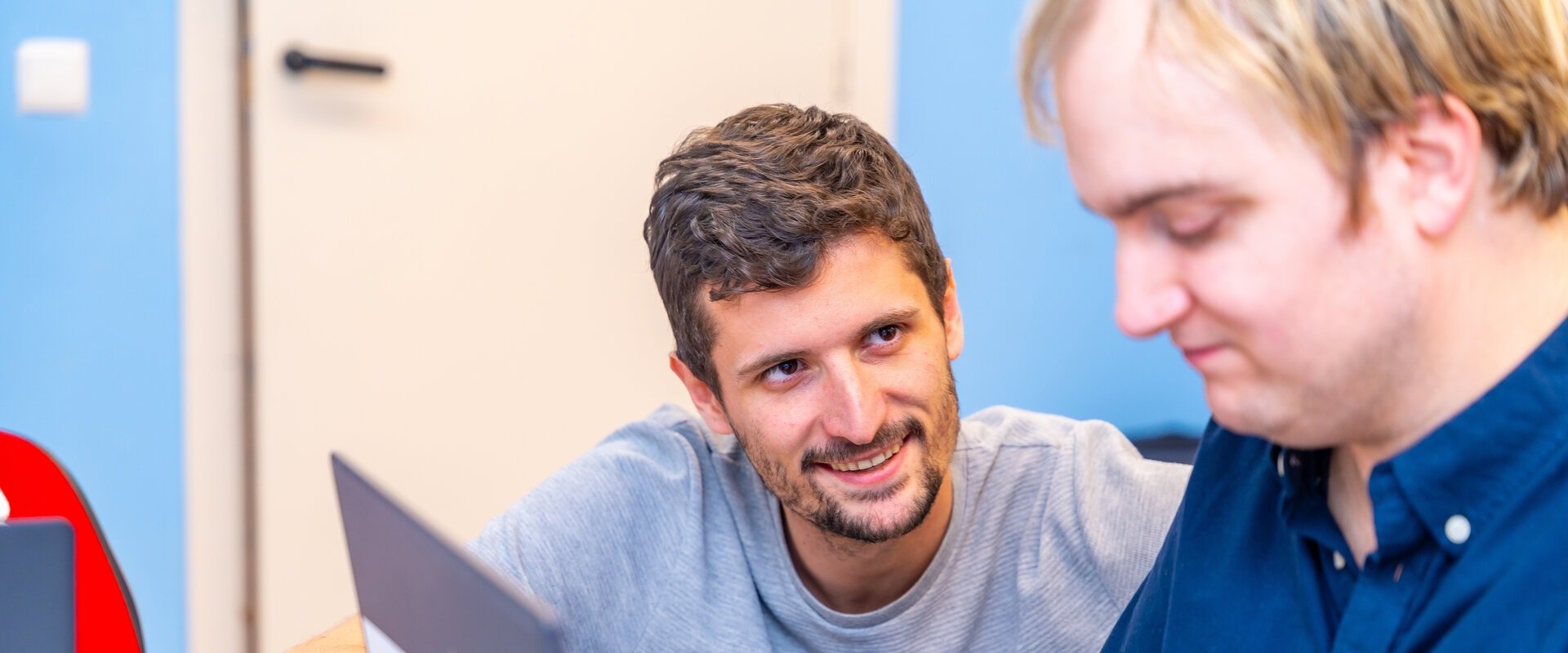 Male support worker helping a man with using a laptop