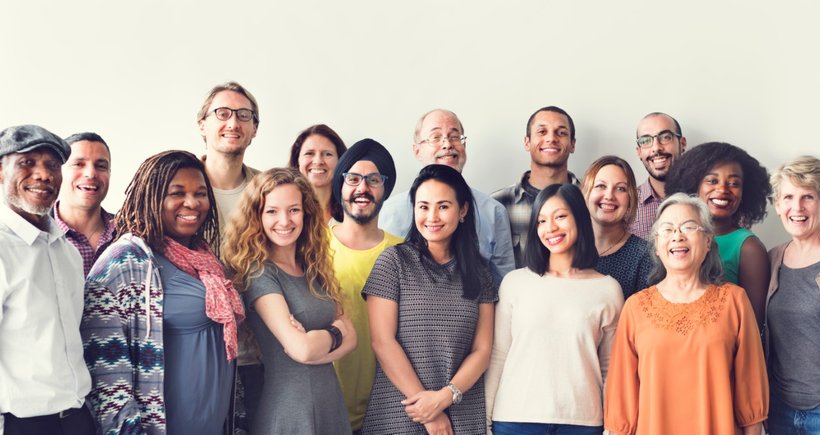 Diverse group in unique outfits, all smiling together.